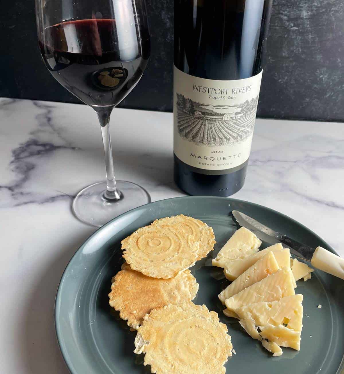 Marquette red wine served with a plate of cheese and crackers.
